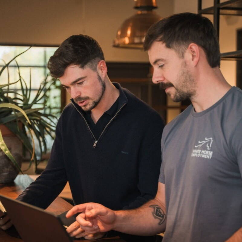 Two of the White Horse discussing something they're looking at on a laptop